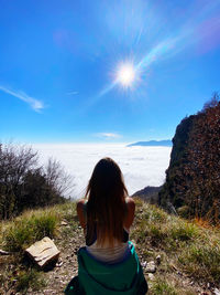 Rear view of woman against sky above the clouds in the mountains