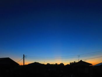 Silhouette electricity pylons against clear sky during sunset