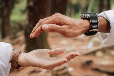 Cropped hands of couple gesturing in forest