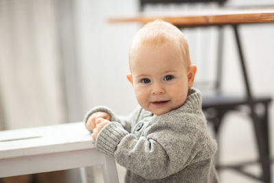 Baby boy himself is standing by the chair, the concept is the first steps and safety. 