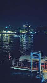 Illuminated cityscape by sea against sky at night