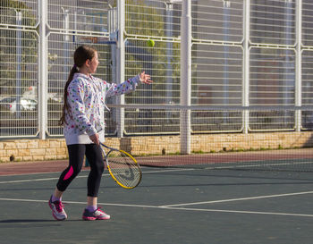 Full length of girl playing tennis in court