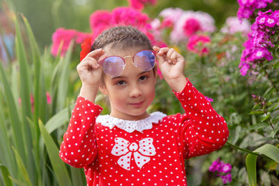 Portrait a little girl in a red dress with polka in glasses