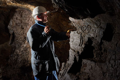 Man wearing helmet standing in cave