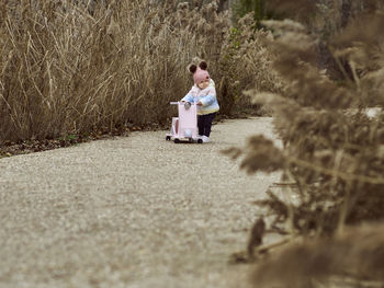 A 1 year old baby girl is with a pink motorcycle outside