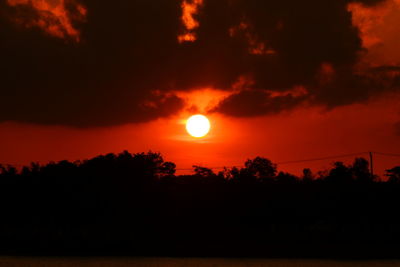 Silhouette trees against orange sky