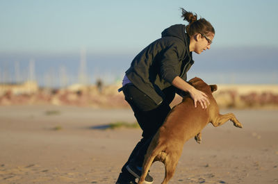 Low section of person riding horse on beach