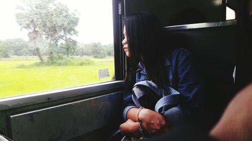 Young woman looking through window while traveling in train