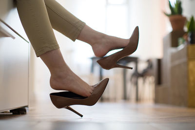 Low section of woman wearing high heels at home