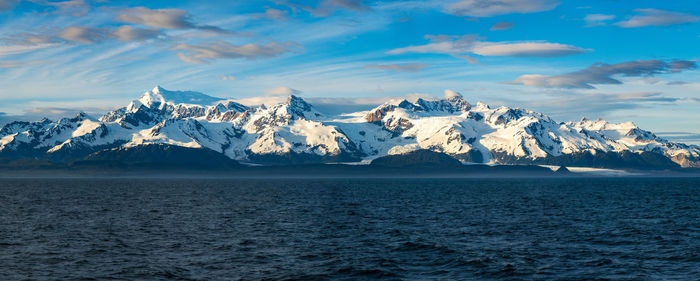 Scenic view of sea and snowcapped mountains against sky