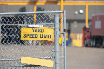 Close-up of yellow sign on chainlink fence