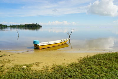 Boat moored on beach against sky