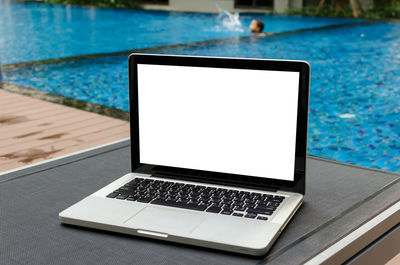 Laptop on lounge chair at poolside