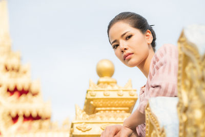 Low angle view portrait of woman standing by railing