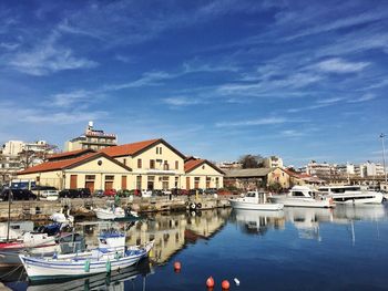 Boats moored at harbor against blue sky