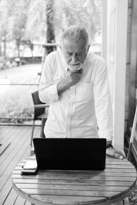 Man using mobile phone while sitting on table