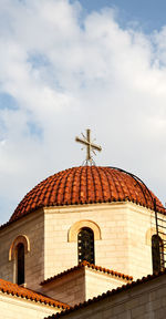 Low angle view of cross on roof of building against sky