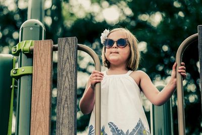 Girl looking away while standing on play equipment at park