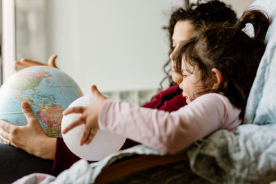 Mother and daughter playing with earth globe