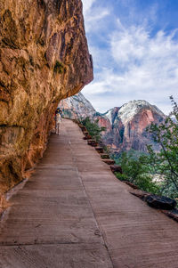 Walkway amidst rock formation against sky