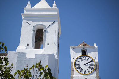 Low angle view of clock and bell tower of church against clear blue sky