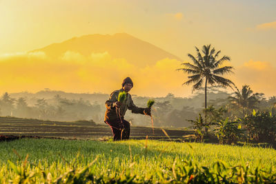 Man standing on field against sky during sunset