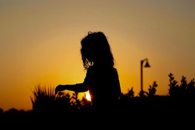 Silhouette people on field at sunset