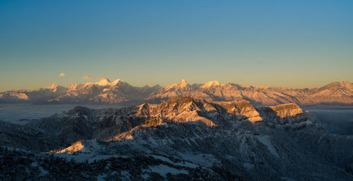 Scenic view of snowcapped mountains against clear sky during sunset