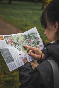 Rear view of woman reading book at park