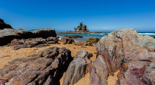 Rocks on beach against blue sky