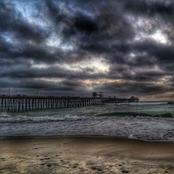 Pier on sea against cloudy sky