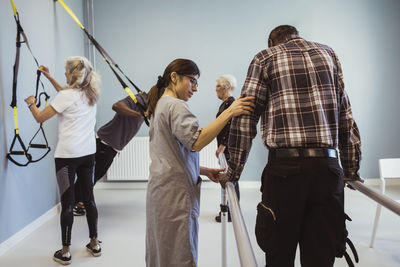 Female nurse assisting senior man to walk in nursing home