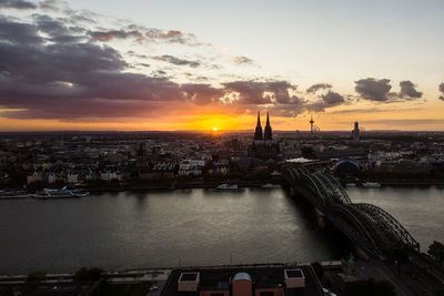 Bridge over river in city during sunset