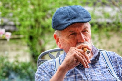 Senior man smoking cigar while sitting in yard