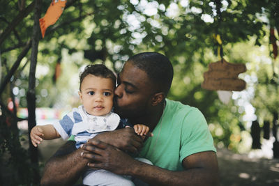 Close-up of father kissing baby boy at park