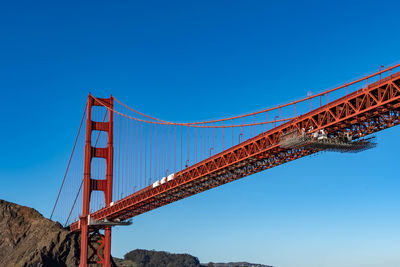 Low angle view of suspension bridge against clear blue sky