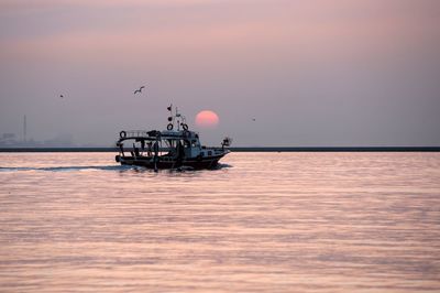 Silhouette boat in sea against sky during sunset