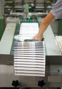 Stack of books with worker working at production line in factory