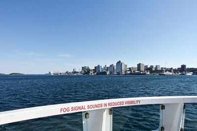 Sea by city buildings against sky