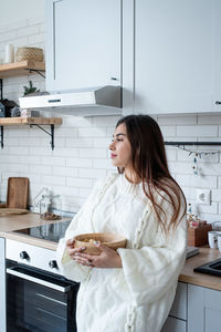 Portrait of young woman standing in kitchen