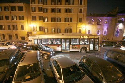 Cars on illuminated street by buildings in city at night