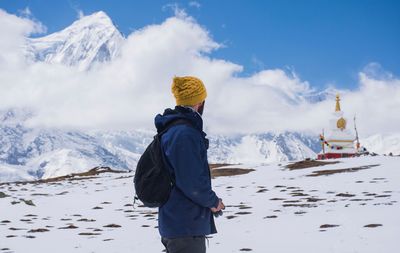 Side view of man standing on snowcapped mountain against sky