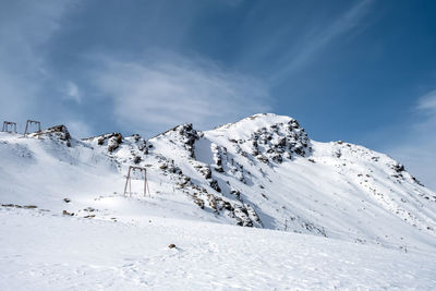 View of the mountain range, steep slopes and snow-capped rocky peaks with supports for the cable car 