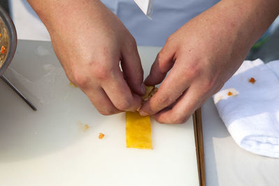 Cropped hands of chef making sushi on table