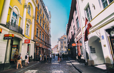 People walking on street amidst buildings in city