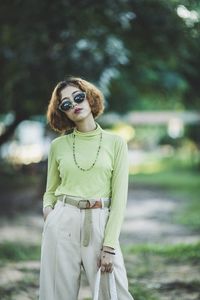 Portrait of young woman wearing sunglasses standing in park