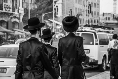 Rear view of people standing on street in city