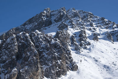 Low angle view of snowcapped mountains against clear blue sky