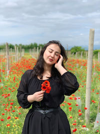 Portrait of young woman standing against trees