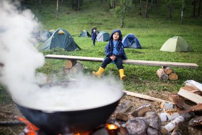 A child sits in a campground next to a bonfire
